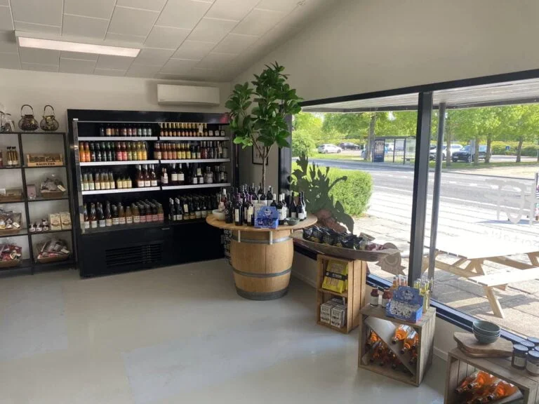 Vinbutik med flasker, snacks og sollys gennem vinduer
